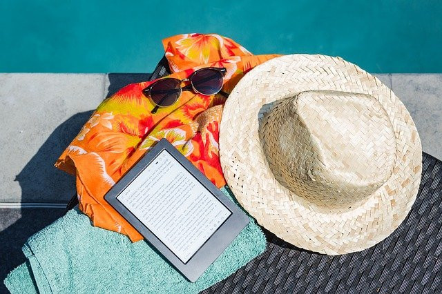 Cappello, lettore ebook e asciugamano a bordo piscina, foto